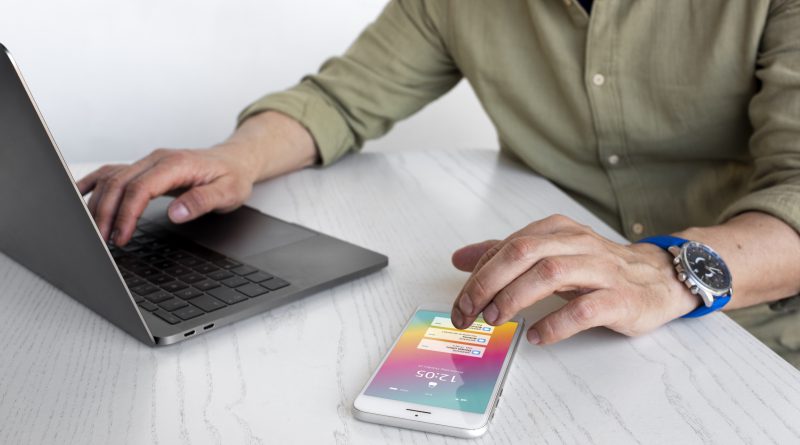 Osoba pracująca nad tworzeniem aplikacji webowych na laptopie i smartfonie.