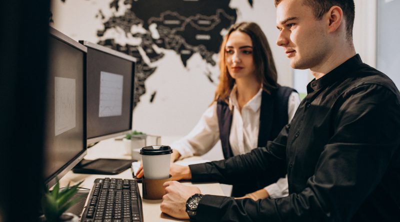 Specjaliści IT pracują nad projektem outsourcingu IT przy stanowisku komputerowym w biurze.