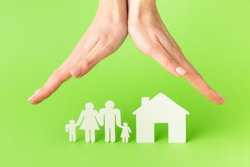 Dłonie wskazujące na postać domu i rodziny - ubezpieczenia majątkowe