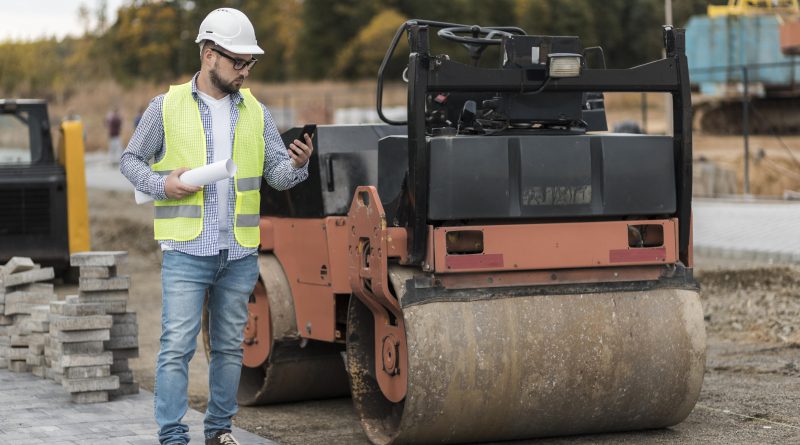 Inżynier na budowie sprawdza postęp prac przy walcu — wynajem walca drogowego w praktyce
